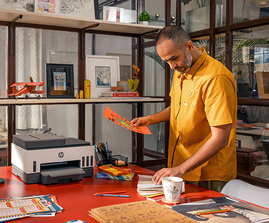 Imagen de un hombre con impresora HP Smart Tank sobre un mue...